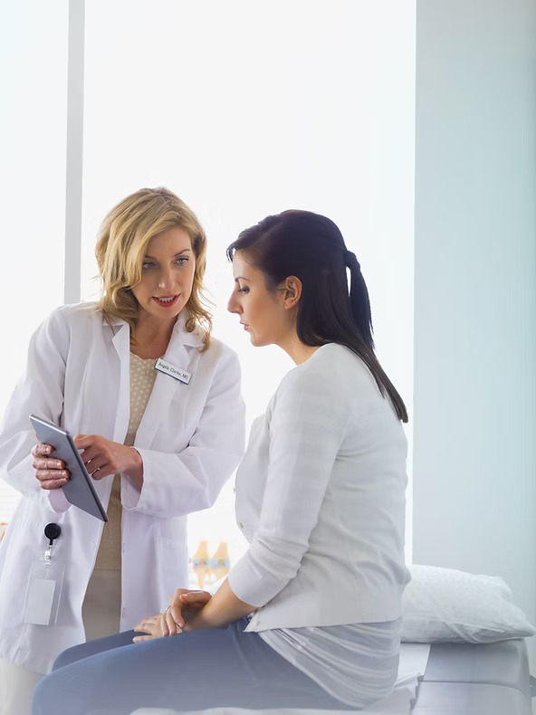 Healthcare professional showing information on a tablet to a patient in a clinic setting.